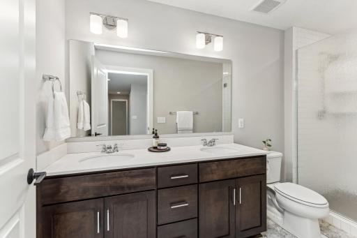 This upper level 3/4 bath has a double vanity and a shower with privacy glass create a luxurious and functional bathroom space, offering both convenience and a touch of elegance.
