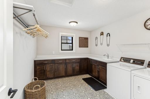 The spacious laundry room features a sink, ample countertops, and cabinetsâa functional and organized space for all your laundry needs