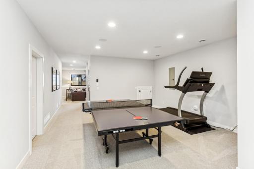 The lower level also includes a dedicated workout and recreation space, perfect for both fitness enthusiasts and those looking to unwind with some friendly competition. This area is thoughtfully designed to accommodate various activities