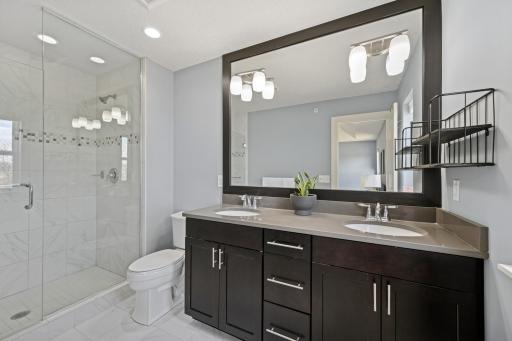 A private 3/4 bath adds luxury to the primary suite with a double sink vanity, and tiled shower.
