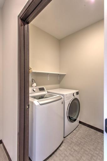 nice size laundry with shelving and folding counter on opposite wall