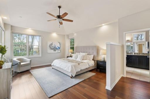 The Primary bedroom suite located on the main levelhas walls of windows, custom blinds and nature views