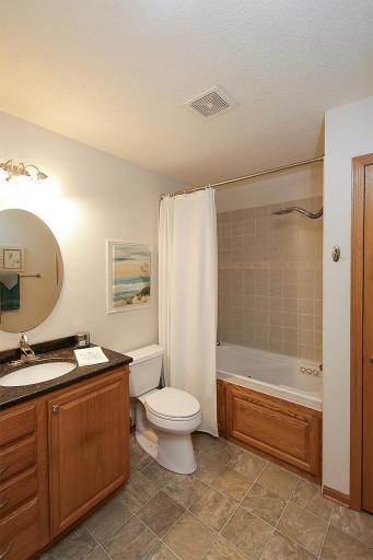 The guest bathroom features an oak vanity with a granite countertop, and a relaxing whirlpool jacuzzi tub.
