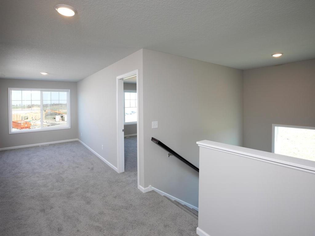 PHOTO OF A DIFFERENT HOME WITH SIMILAR PLAN & FINISHES. Upper level staircase and loft views. Photo may not depict actual plan, materials, & finishes.