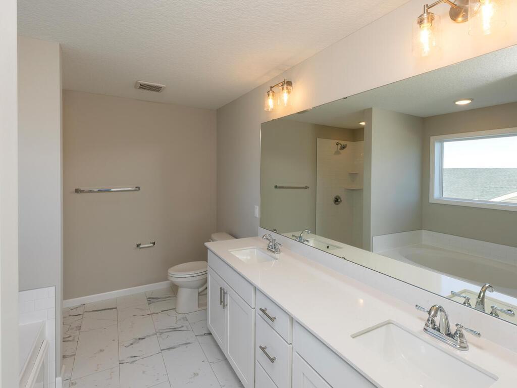 PHOTO OF A DIFFERENT HOME WITH SIMILAR PLAN & FINISHES. Primary deluxe bath features. Photo may not depict actual plan, materials, & finishes.