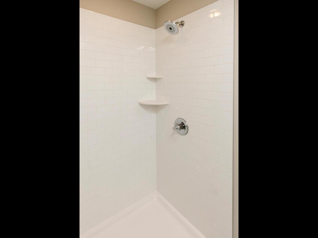 PHOTO OF A DIFFERENT HOME WITH SIMILAR PLAN & FINISHES. Primary suite bath features a 4' shower with tile wall surround and shelves. Photo may not depict actual plan, materials, & finishes.