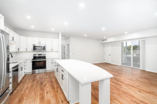 The open-concept kitchen serves as the heart of the home, featuring a spacious center island with stunning quartz countertops, perfect for meal preparation, casual dining, or entertaining guests.