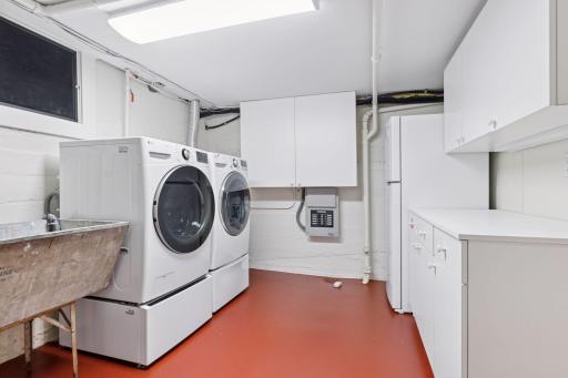 Large lower level laundry room with built-in cabinetry and a double laundry sink. Panel is for the whole house generator. 2nd refrigerator.