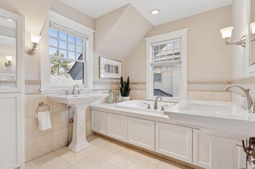 Full hall bath with two pedestal sinks, large soaking tub, walk-in shower, and built-in storage.