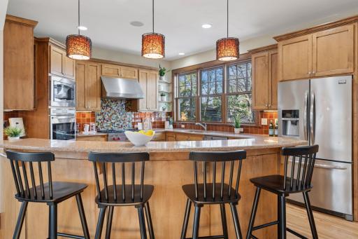 Curved peninsula with bar height seating with pendant lighting