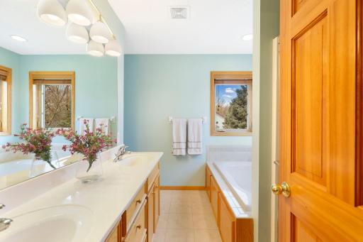 Owner's bathroom with large oak vanity cabinet w/ dual sinks, modern sconce lighting and tile flooring