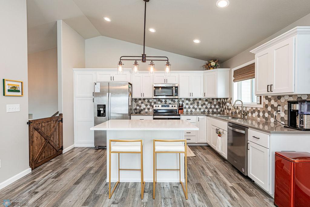 All-white kitchen. Tile backsplash. Stone counters. Breakfast bar island.
