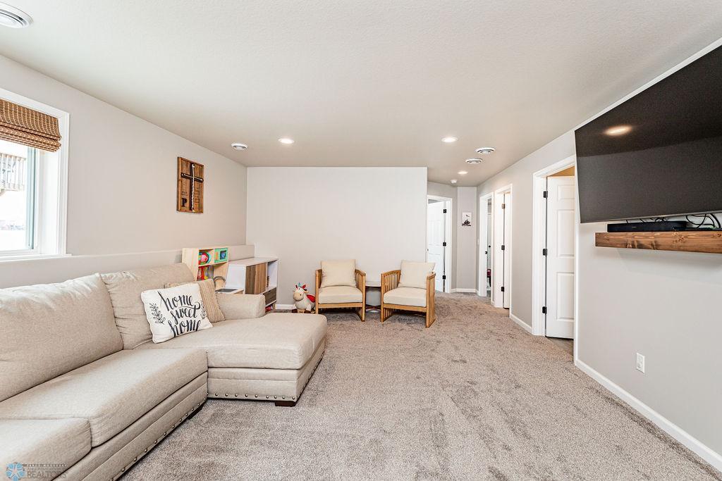 Spacious family room with neutral paint, cozy carpet, recessed lighting.