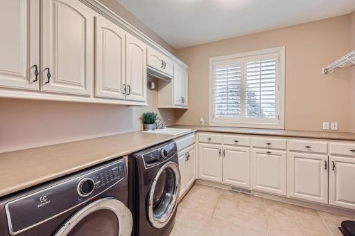 Huge laundry room on main level with abundance of countertops, cabinets, closets and storage