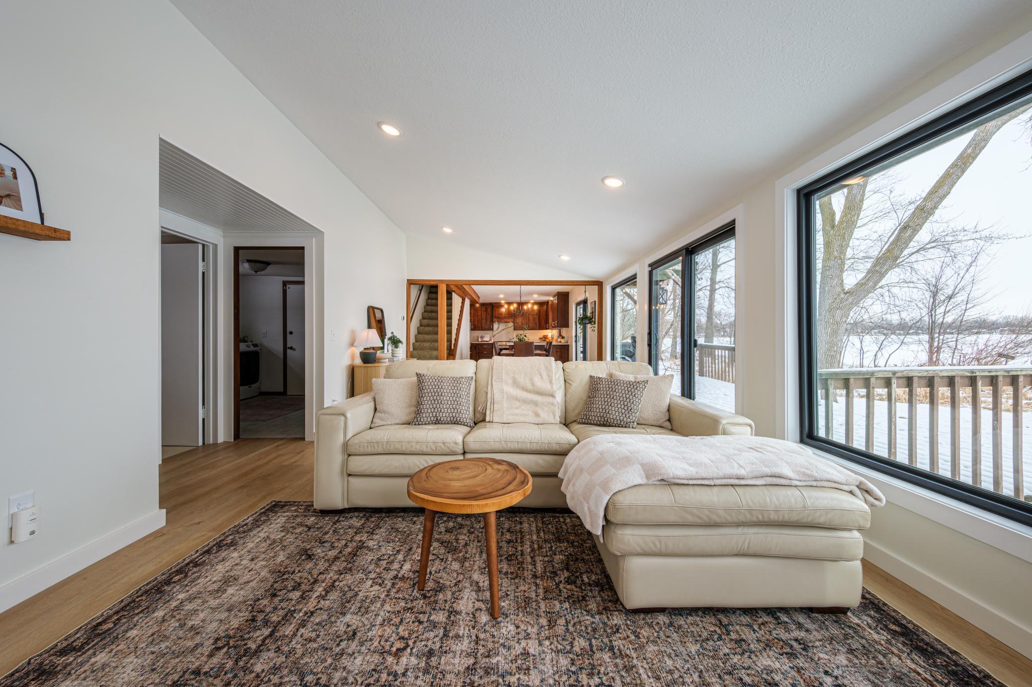 Living room features large windows with views of Lake Manuella, vaulted ceilings, and recessed lighting.