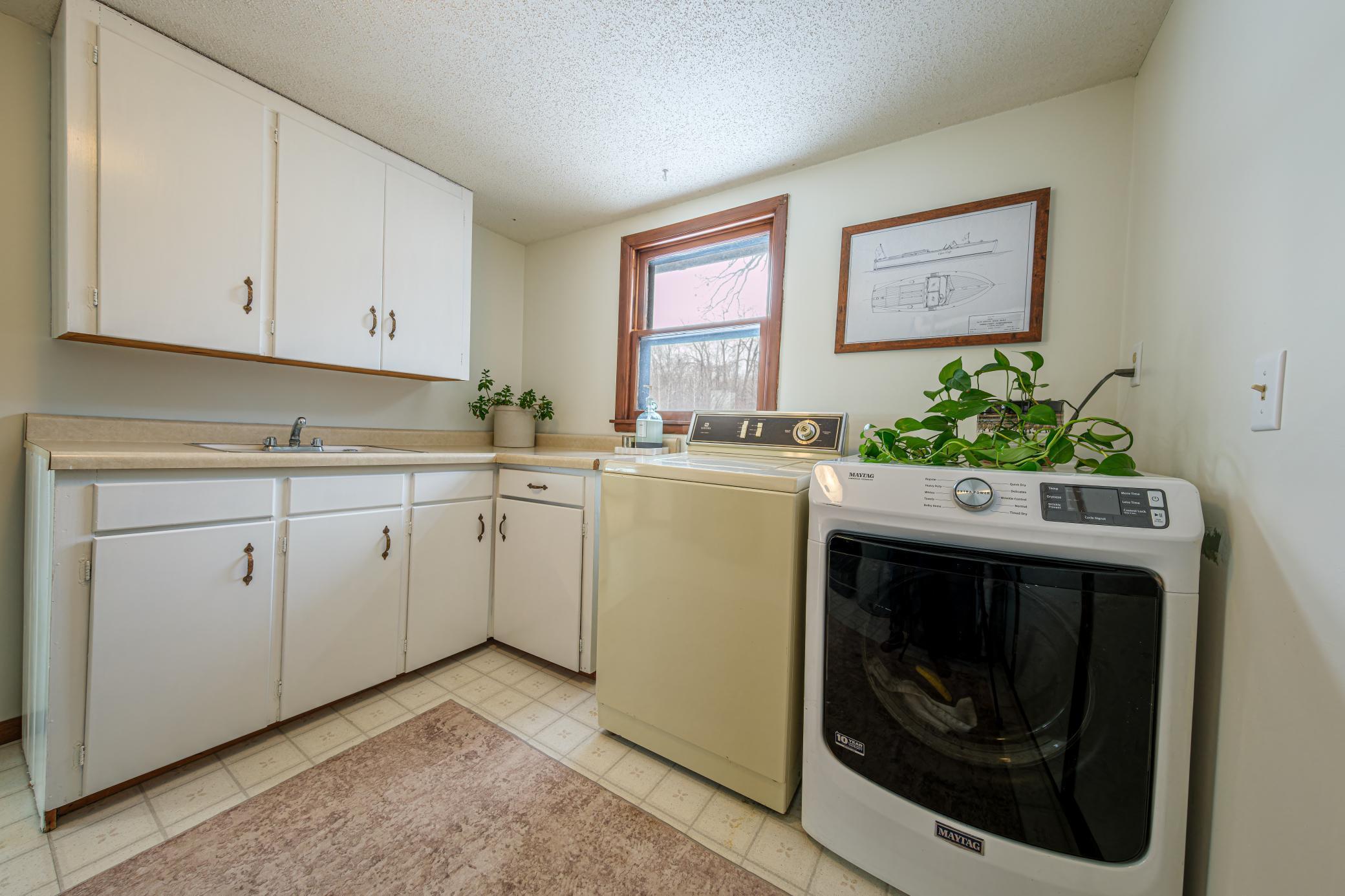 Main floor laundry room features laminate countertops, a utility sink, and freshly painted cabinets.