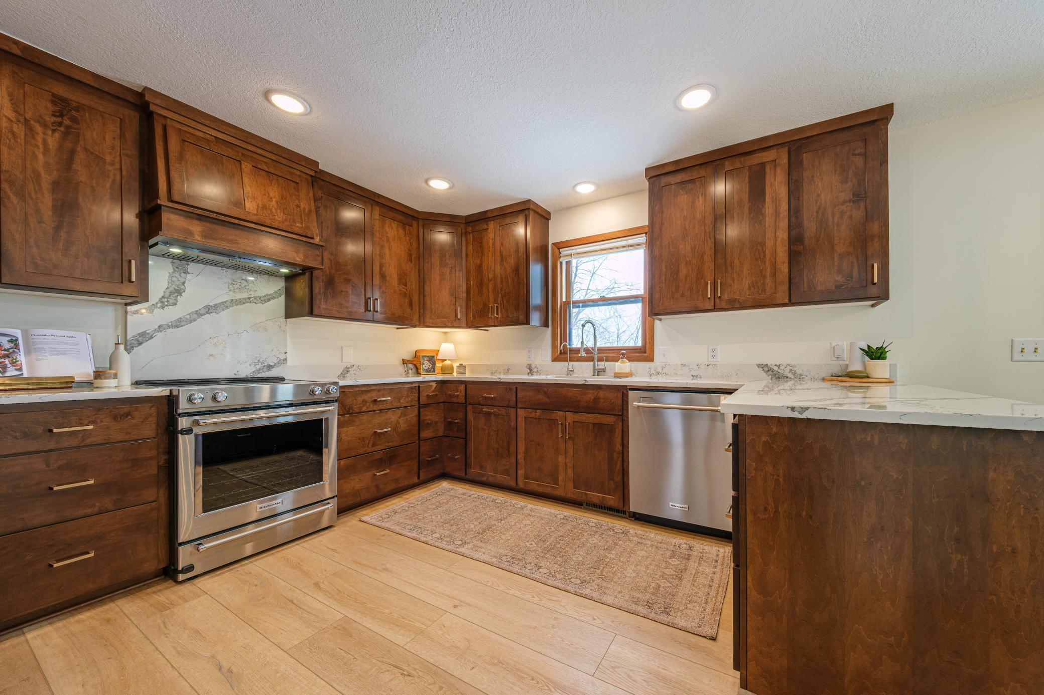 Updated kitchen features custom maple cabinets, quartz countertops and backsplash behind range, SS Kitchenaid appliances, an Aquatru RO system, corner pullout drawers, and a pantry with pullouts.