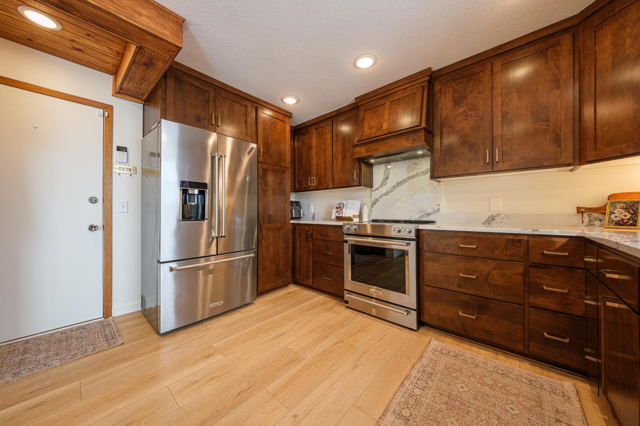Newly remodeled kitchen (2024) features Schlangen's custom maple cabinets, quartz countertops, quartz backsplash behind range, and Kitchen Aid SS appliances.