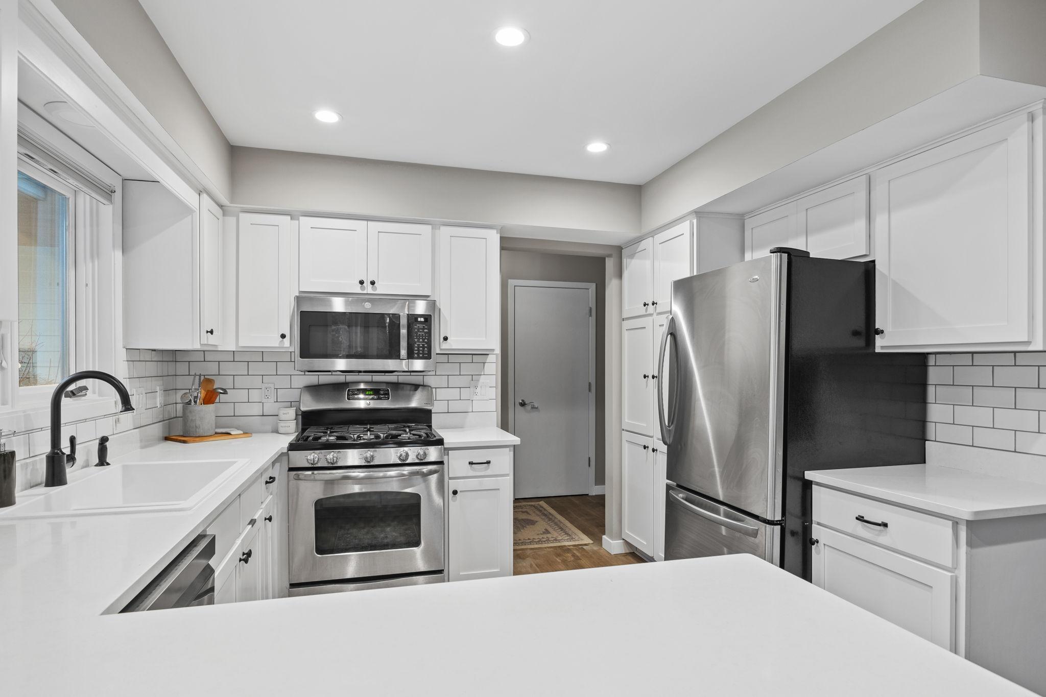 Another view of the polished kitchen. The door through the entry way is the front foyer coat closet and the mudroom/laundry and garage entrance is the door to the left of that one.