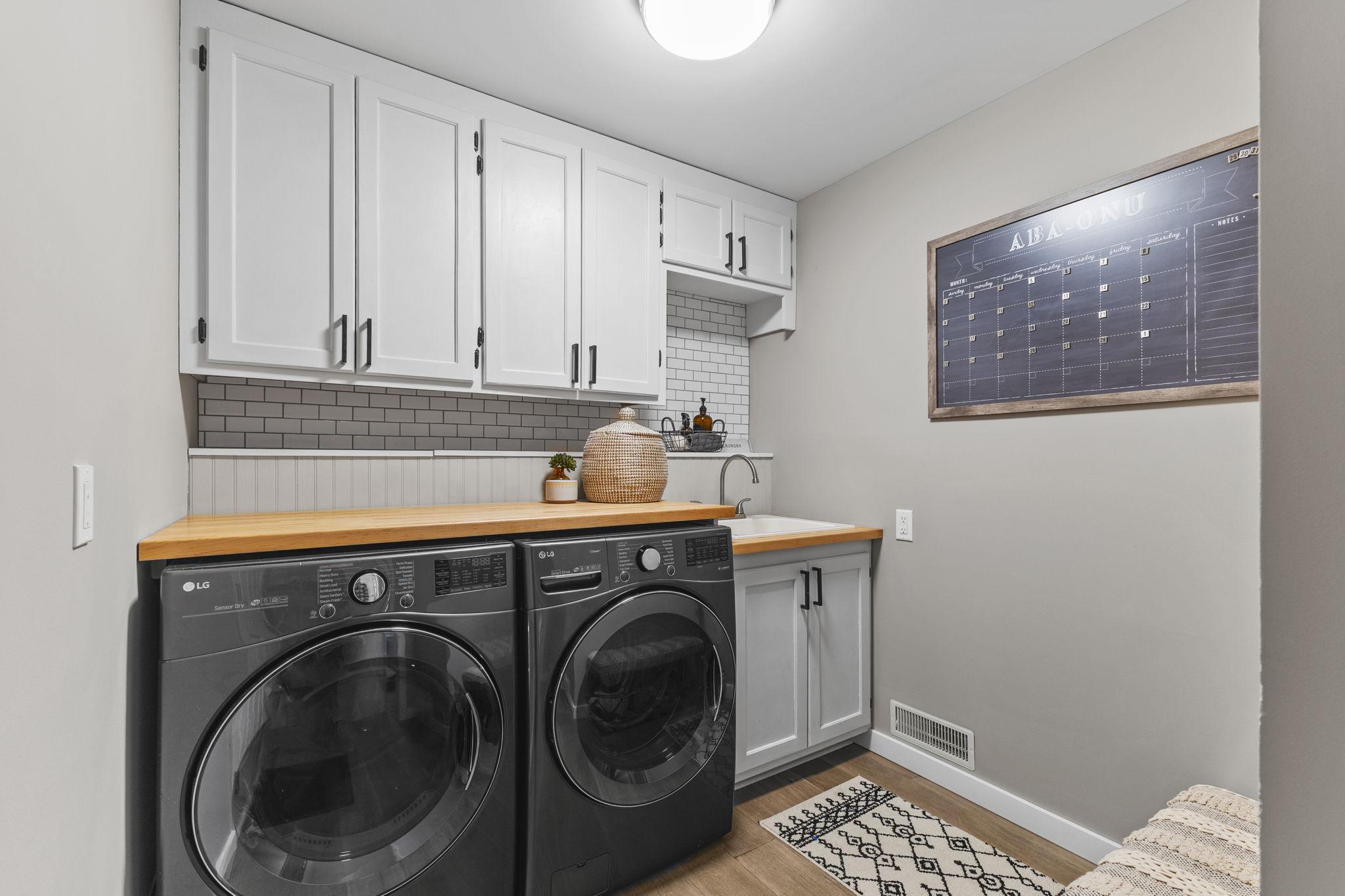 Main level laundry room-where style meets function! This beautifully designed space features an LG washer and dryer, topped with a butcher block countertop for folding and organizing. Not seen is the open locker system on the other wall!