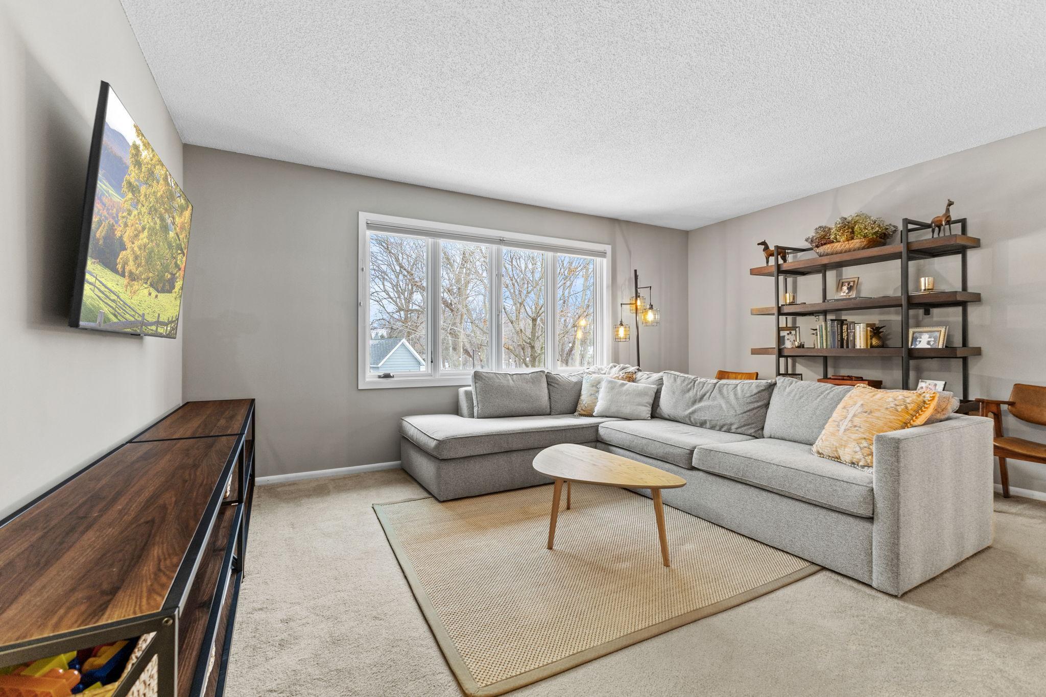 This is the upper level living room. Natural light floods the room through large windows, offering a beautiful outdoor view and creating an airy, open atmosphere.
