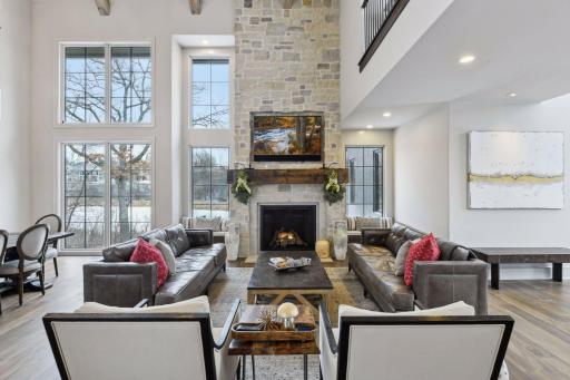 Custom windows frame the natural stone hearth with reclaimed wood beam mantle