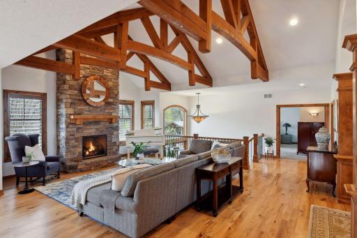 Stunning architecture with rustic beams, soaring ceilings, gorgeous hickory floors, and a floor to ceiling stone fireplace – such a warm and inviting space to come home to!