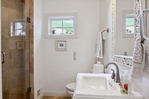 Main floor 3/4 bathroom with beautiful tiled shower and pedestal sink.