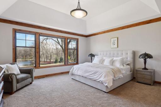 Spacious main floor primary bedroom with ensuite bathroom and custom closets â amazing views and automatic two-way Hunter-Douglas black-out shades.