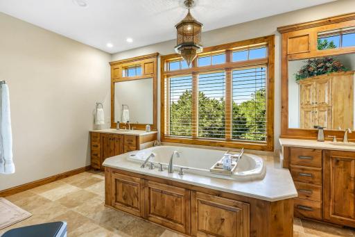 Luxurious primary bath with in-floor heat, Travertine tiles, separate sinks, a jacuzzi tub walk-in shower â and a Japanese Toto toilet.