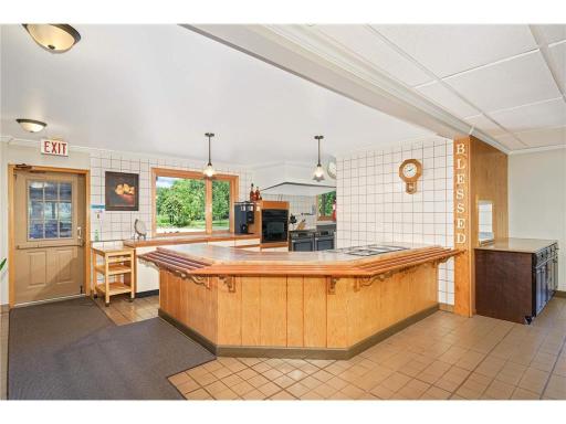 The serving area with the kitchen in back and the dining area to the right flows directly from the steps to the lower level.
