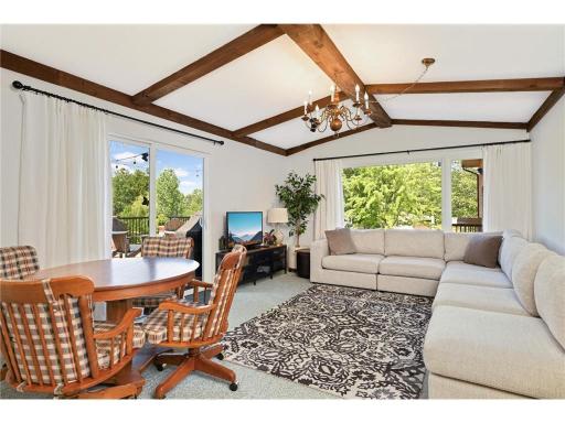 This living room and dining room are part of the separate living quarters . The patio doors lead to an amazing deck overlooking the yard and pond