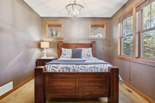 This inviting main floor bedroom offers a tranquil retreat bathed in natural light, thanks to its abundance of windows.