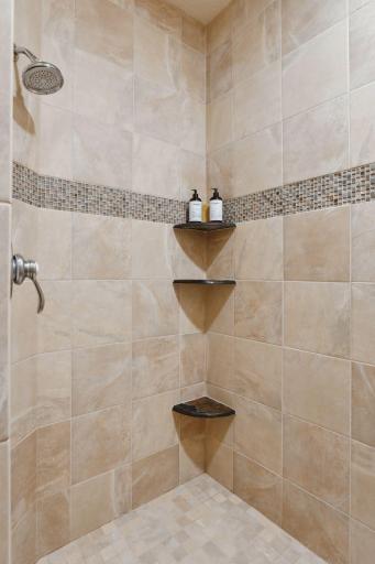 A large walk-in shower, beautifully finished with custom tile, transforms this space into a personal spa retreat.
