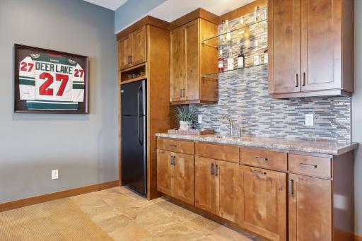 The stylish bar features a set of glass shelves that create a gallery-like display for your premium selections. A full-size refrigerator keeps your beverages perfectly chilled, ensuring that you always have refreshments on hand.