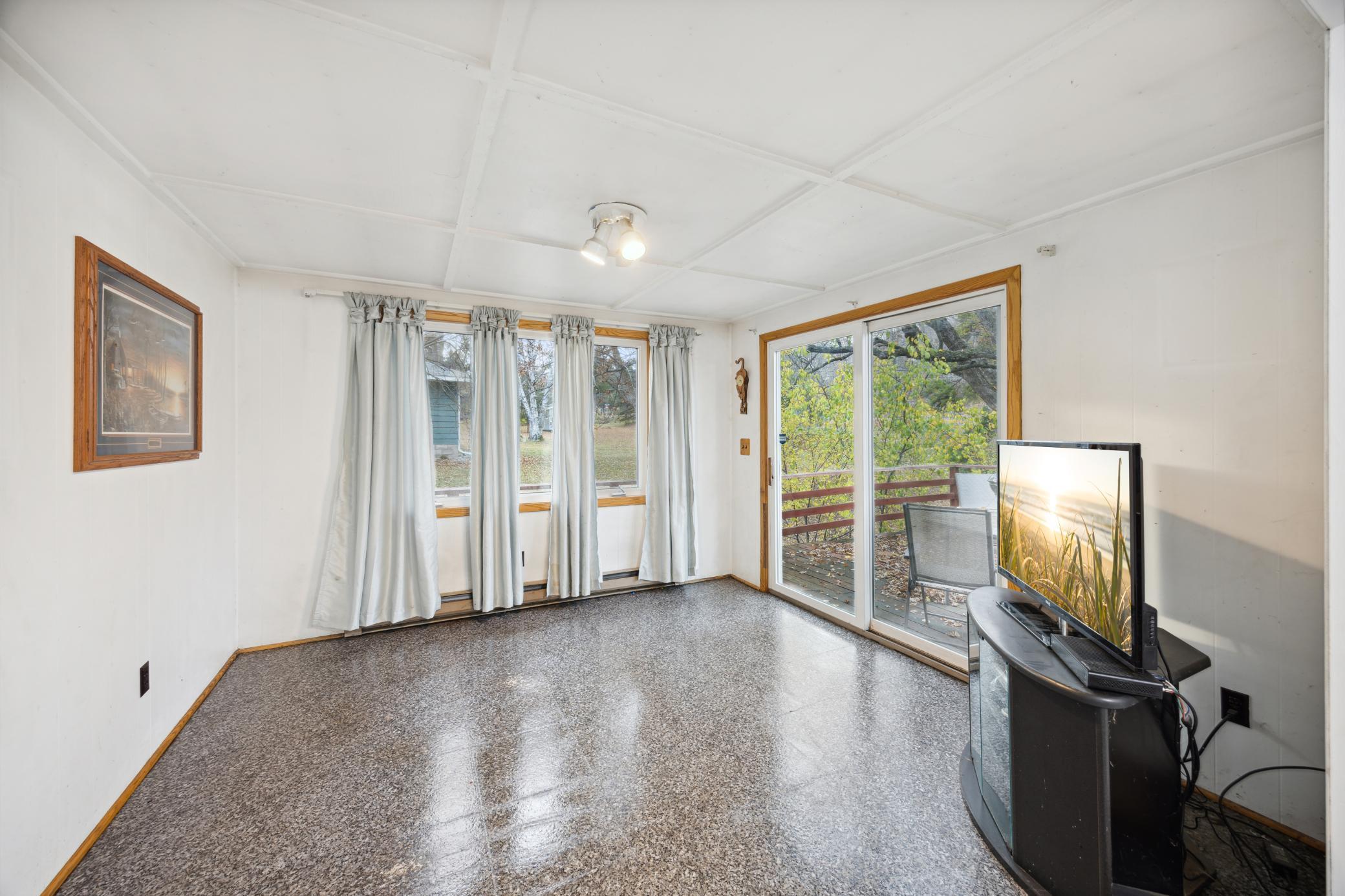 The sunroom is filled with natural light. The sliding door leads onto the deck.