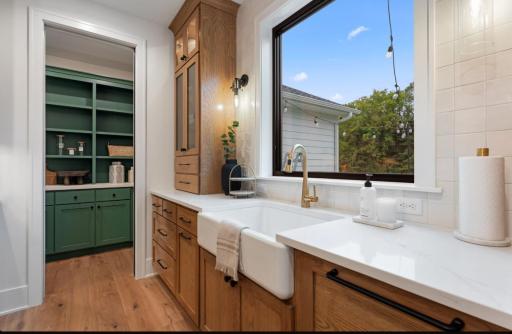 Large window at Kitchen sink has tall cabinets with glass doors and rear prep pantry.