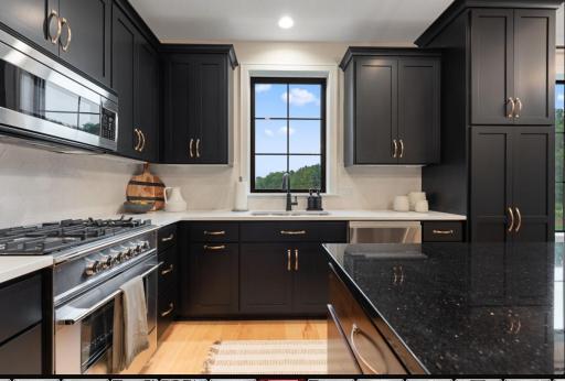 Designer ADU on main level shares four car garage includes a private entry, deluxe kitchen with custom cabinetry, large island with eating space, vaulted great room with fireplace and large windows.