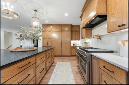 Full size frig and freezer columns with wood panels, ice machine, and hidden appliance garage with retractable doors.
