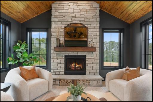 Cozy sunroom features wood burning fireplace with stone hearth, tongue and groove ceiling and walls of windows to enjoy the private natural setting