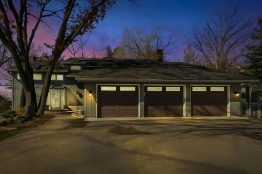Striking modern home with three-car garage, welcoming front entry, and elegant exterior lighting, set against a serene evening backdrop.