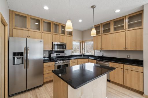This stunning kitchen boasts high cedar cabinets with elegant lighting, adding warmth and character, while a spacious island provides the perfect centerpiece for cooking and gathering.