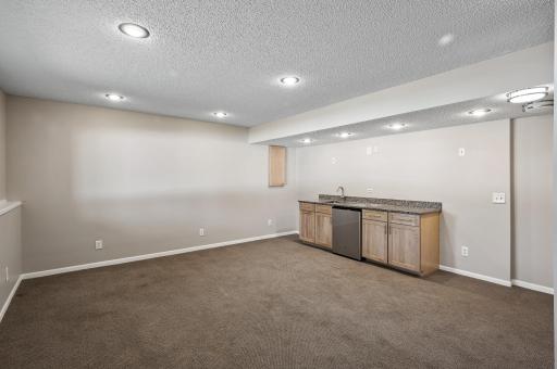 30 Lower level family room bar area with a sink and newly installed refrigerator