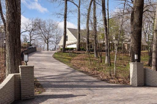 Grand paver driveway leads to a oversized 3-car Garage, with storage shed at top/left.