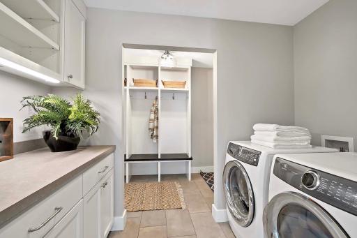 This spacious laundry room is equipped with ample counter space and storage, making chores easy and efficient.