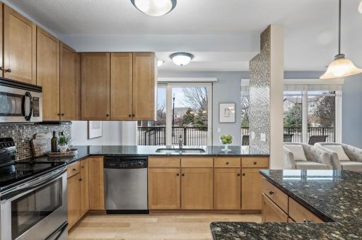 Kitchen has maple cabinetry, glass/tile backsplash & newer granite counters