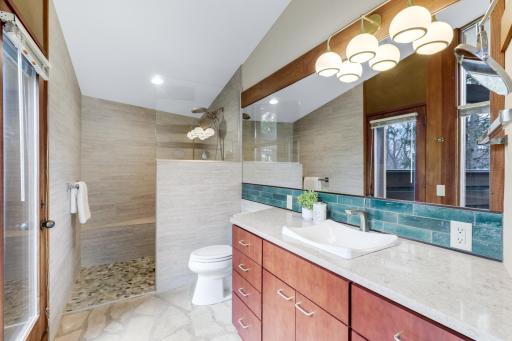 Remodeled primary bathroom with curbless shower stall and floor to ceiling tile.