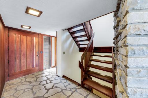 Foyer features the massive cedar and copper front door, flagstone stone flooring and open mahogany stairase.