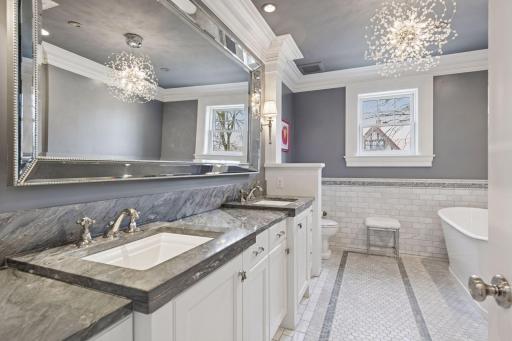 Primary bath with stone and marble finishes, double vanity, luxurious tile, walk-in shower, and separate soaking tub. Heated floors.