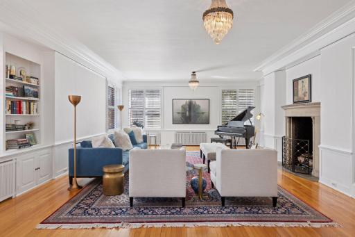 Spacious forma living room with south-facing windows and a large gas log-set fireplace. Built-in library shelving, cabinets, and wainscoting.
